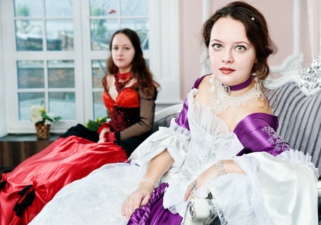 Two women sisters in medieval dresses on the sofaの写真素材