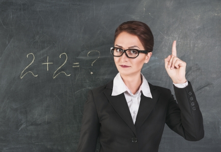 Woman teacher in glasses teaching maths and showing fingerの写真素材