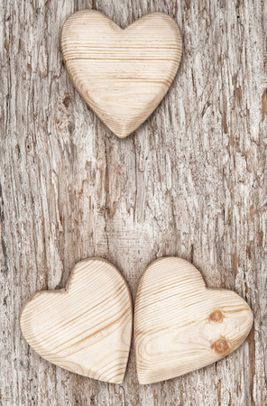 Three wooden hearts on the old wood backgroundの写真素材