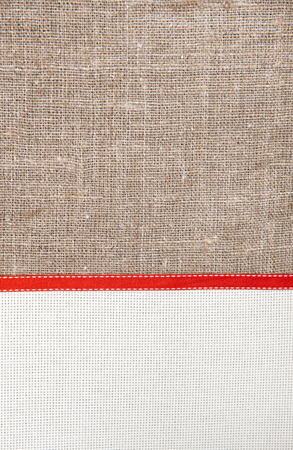 Christmas card with canvas, red ribbon on burlap backgroundの写真素材