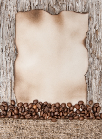 Aged sheet of paper with coffee beans on the old wood backgroundの写真素材