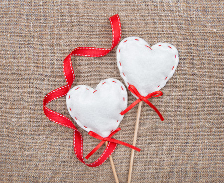 Textile hearts and ribbon on sacking backgroundの写真素材