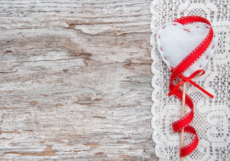 Valentine card with textile heart on lacy cloth and old wood backgroundの写真素材