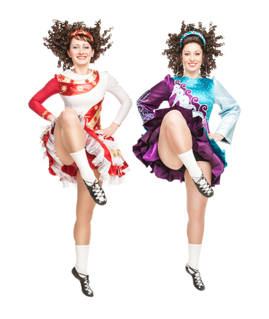 Two young women in irish dance dress and wig dancing isolatedの写真素材