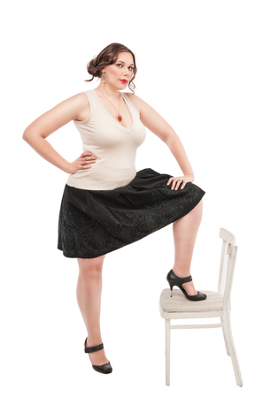 Beautiful plus size woman with chair posing on white backgroundの写真素材