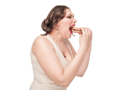 Beautiful plus size woman eating hamburger isolatedの写真素材