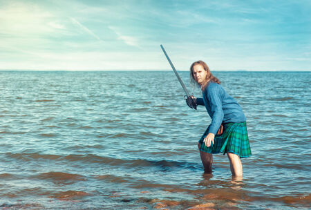 Brave man with sword in scottish costume and the seaの写真素材