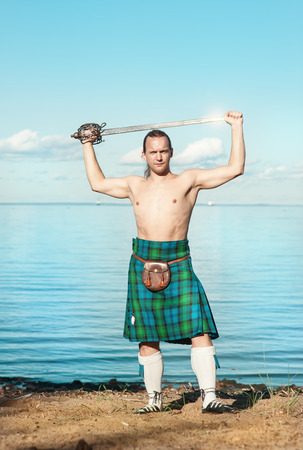 Brave man with sword in scottish costume near the seaの写真素材