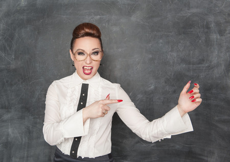 Beautiful fashion woman pointing on something in her hand on the blackboard backgroundの写真素材