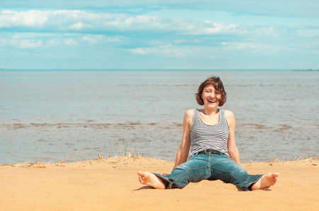Happy young woman sitting on the beach outdoorの写真素材