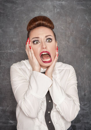 Scared teacher in white blouse on the blackboard backgroundの写真素材