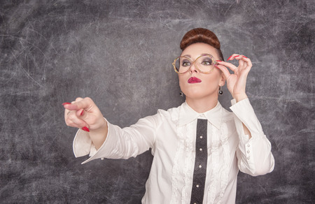 Strict teacher in eyeglasses showing on someone by her finger の写真素材