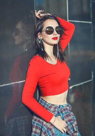 Young beautiful girl in red blouse with sunglasses outdoorの写真素材