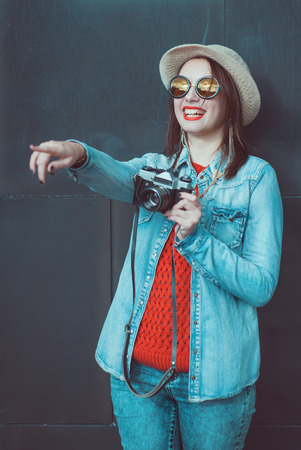 Young happy beautiful hipster girl with retro camera near wallの写真素材