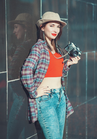 Young beautiful hipster girl with retro camera near wall outdoorの写真素材
