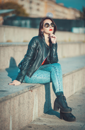 Young fashion beautiful girl in leather jacket and sunglasses outdoor in the cityの写真素材