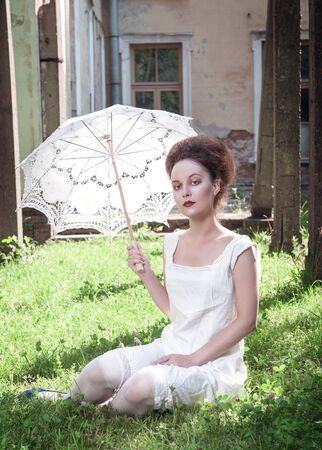 Beautiful young gothic girl in white shirt with umbrella outdoorの写真素材