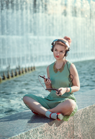 Hipster fashion hipster girl in green dress listening music outdoorの写真素材