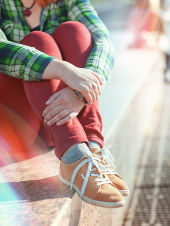 Yellow sneakers on girl legs in hipster style sitting on the bench outdoorの写真素材