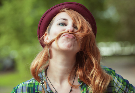 Hipster redhead woman making a moustache with her hair outdoorの写真素材