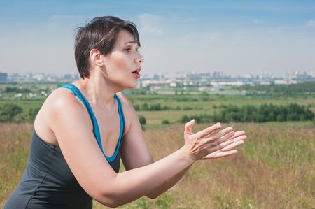 Fitness beautiful plus size woman stretching hands to something outdoorの写真素材