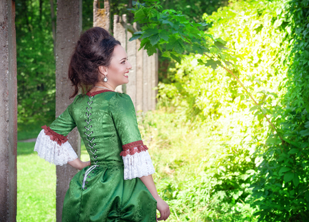 Beautiful young woman in green medieval dress outdoorの写真素材