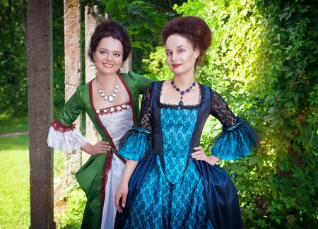 Two young beautiful women in long medieval dresses outdoorの写真素材