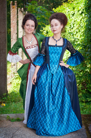 Two young beautiful women in long medieval dresses outdoorの写真素材