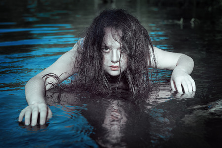 Young beautiful drowned ghost woman in the water outdoorの写真素材