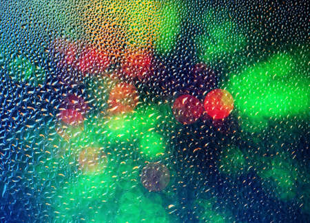 Drops of rain on glass with defocused lights. Abstract blurred colorful background