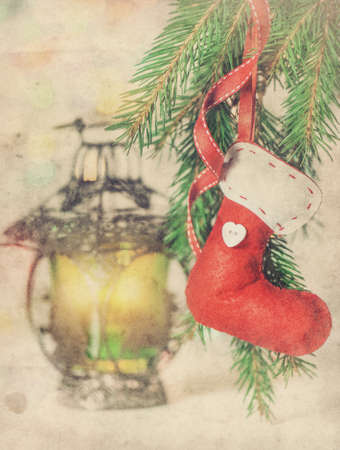 Vintage grunge Christmas card with red sock, fir branch and lanternの写真素材