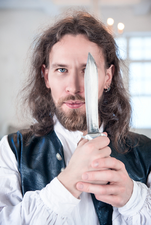 Portrait of young handsome man in medieval clothes with daggerの写真素材