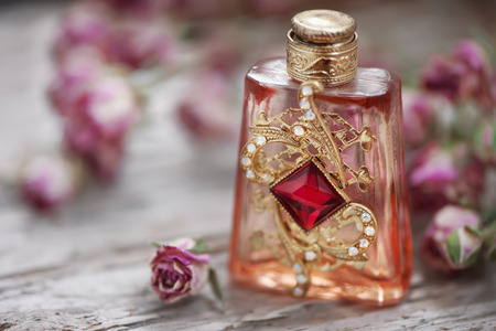 Dry tea roses and vintage perfume bottle on the old wood background
