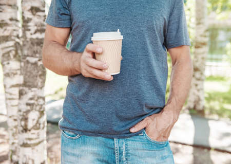 Man holding empty paper coffee cup outdoor. Template mock upの写真素材