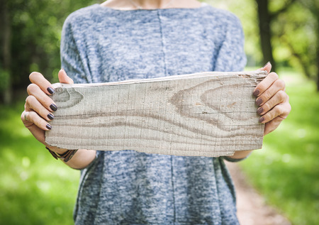 Empty wooden board hold by woman hand outdoor. Template mock upの写真素材