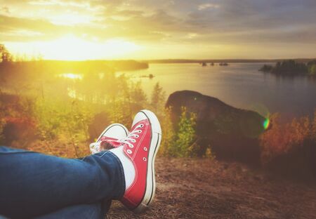 Legs of traveler sitting on the cliff and relaxing. Travel and freedom conceptの写真素材