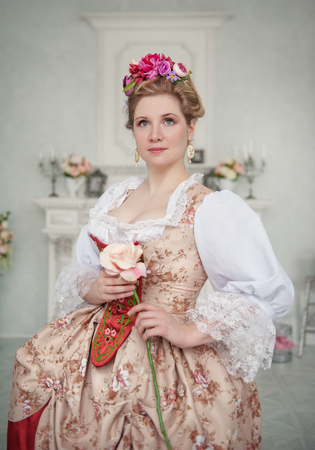 Beautiful woman in medieval dress holding pink roseの写真素材
