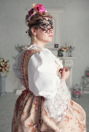 Beautiful woman in old-fashioned historic medieval dress with maskの写真素材