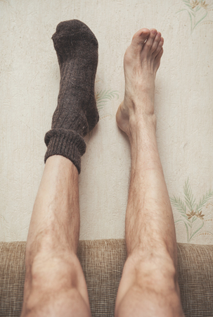Man feet up on the wall in woolen sock. Cozy conceptの写真素材