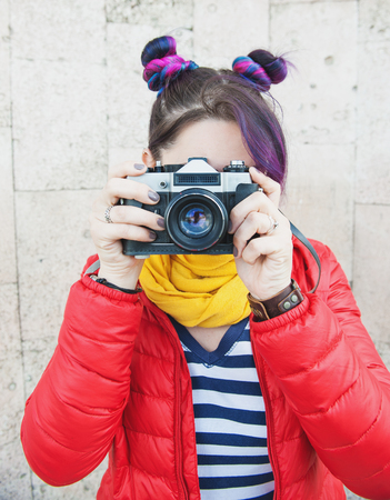 Fashion hipster woman with colorful hair with retro camera over wall backgroundの写真素材