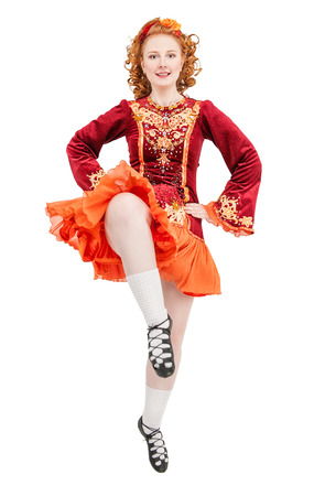 Beautiful woman in red dress for Irish dance jumping isolated on whiteの写真素材