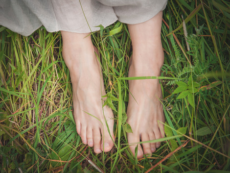 Woman legs standing in grass on summer meadow outdoorの写真素材