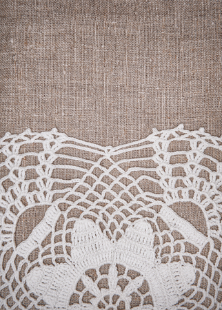 Vintage lace fabric border on the old burlap textile backgroundの写真素材