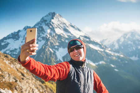 Happy woman hiker on the top of mountain making selfie outdoorの写真素材