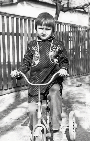 Vintage photo of little girl on old bicycle outdoorの写真素材
