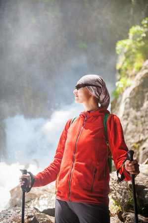 Woman hiker with sticks near waterfall outdoor. Tourism conceptの写真素材
