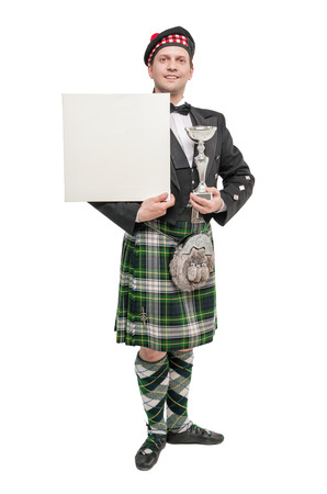 Young man in clothing for Scottish dance with empty banner isolatedの写真素材