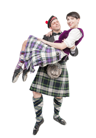 Man in traditioanl Scottish costume holding woman on hands isolatedの写真素材