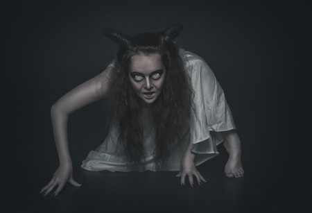 Terrible ghost with horns crawl on dark backgroundの写真素材