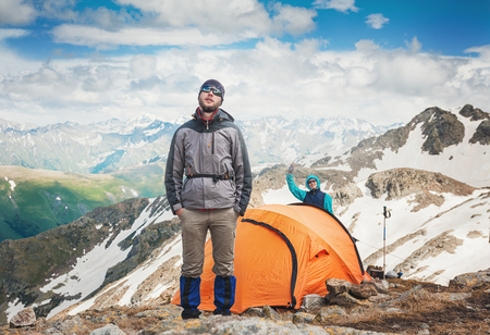 Tourist tent in camp with hiker man among mountain landscape and blue sky outdoorの写真素材